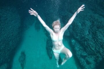 Exploring underwater - an underwater image of a girl with spread arms shot from above