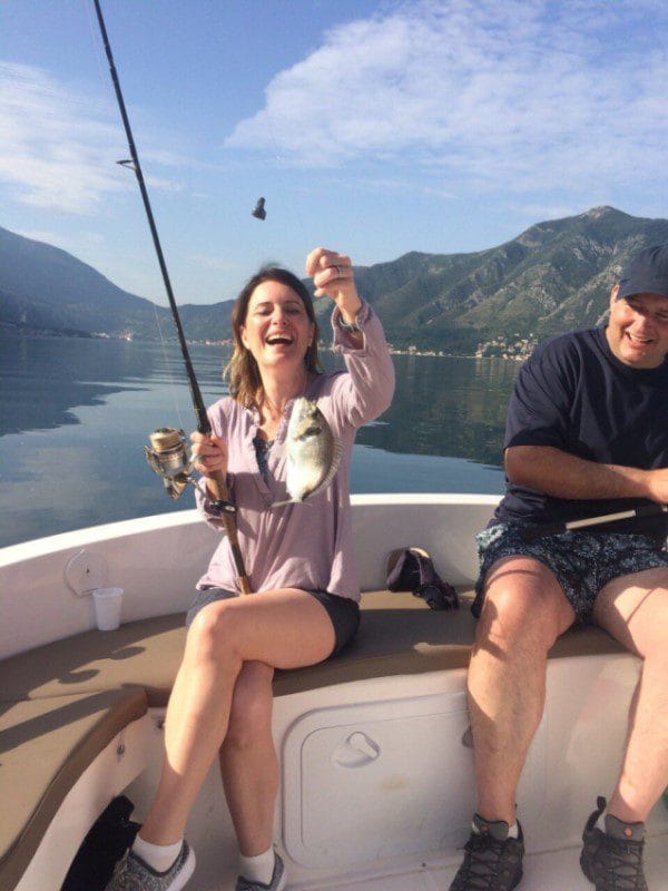 fishing adventure - a happy smiling woman holding the rod with her catch (a gilthead bream)
