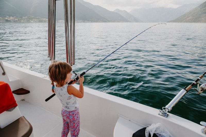 Little girl trying to fish with gear for grownups