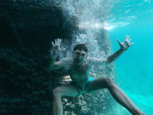 Kotor Boat Tours: Blue Cave - a person making a fun figure in front of the camera under the sea