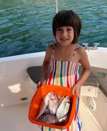 Little girl Lara with a bucket of freshly caught fish